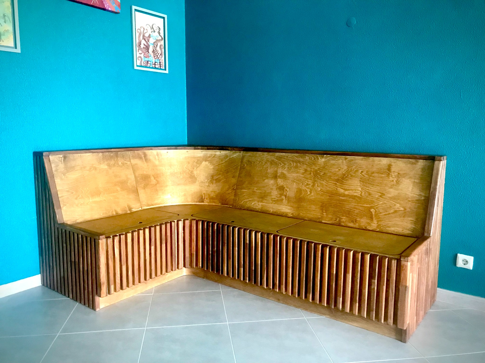 Wide view of a handmade L-shaped corner dining bench with curved ends and vertical timber slats