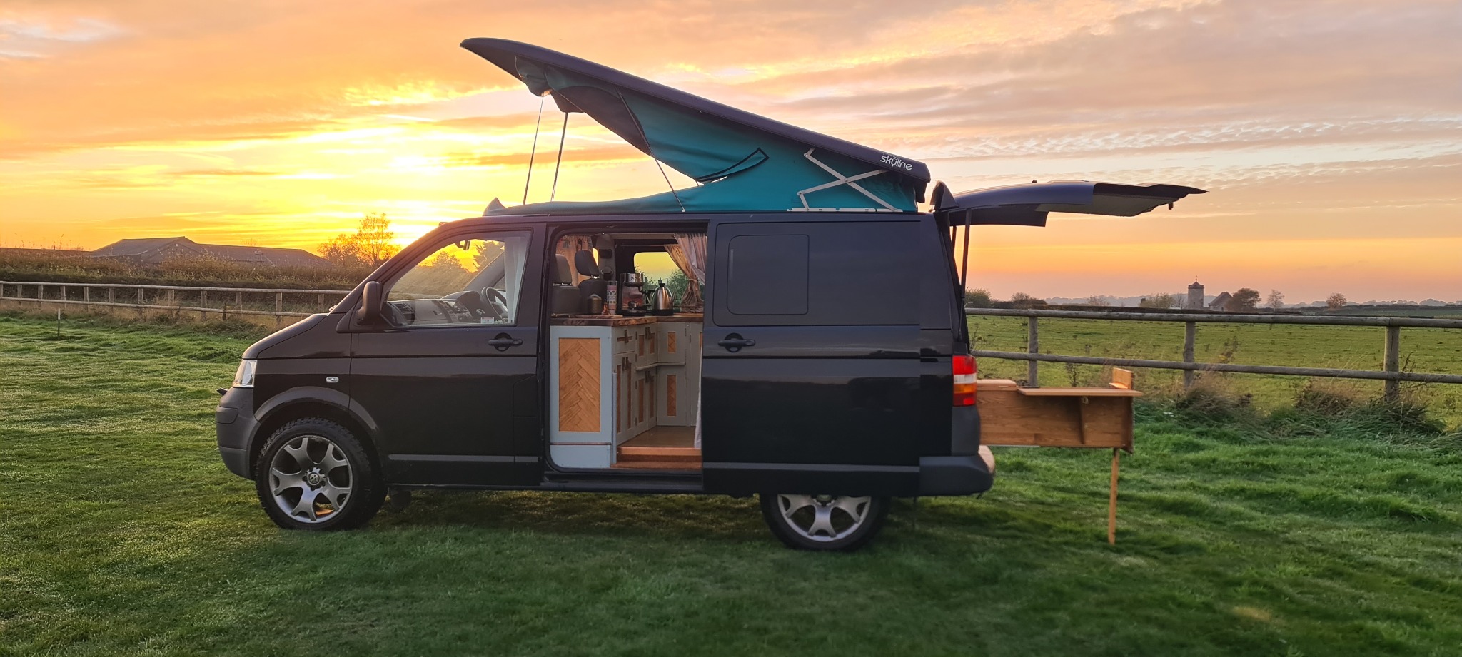Exterior view of the finished campervan conversion against a sunset